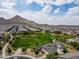 Expansive aerial view of a community with a lush green park and mountain backdrop at 4148 W Dayflower Dr, San Tan Valley, AZ 85144