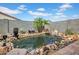 Beautiful backyard pond surrounded by rocks, plants, and tropical trees at 4148 W Dayflower Dr, San Tan Valley, AZ 85144