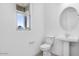 Bright bathroom featuring a pedestal sink, toilet, round mirror, and a window with a view at 8240 E Quintuplet Ave, Mesa, AZ 85212