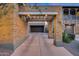 View of porte cochere and driveway leading to garages with brick accents and manicured landscaping at 9439 E Trailside Vw, Scottsdale, AZ 85255
