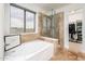 Elegant bathroom featuring a soaking tub, glass-enclosed shower, and a large window at 10219 E Le Marche Dr, Scottsdale, AZ 85255