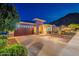 Inviting home exterior features a brick driveway, desert landscaping, and a two-car garage at twilight at 10260 W Pinnacle Vista Dr, Peoria, AZ 85383