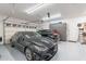 Clean three-car garage featuring epoxy flooring, storage solutions and two parked cars at 10260 W Pinnacle Vista Dr, Peoria, AZ 85383