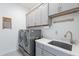 Well-equipped laundry room with gray cabinets, modern washer and dryer, and a convenient utility sink at 10260 W Pinnacle Vista Dr, Peoria, AZ 85383