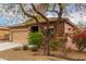 Single-story home with a two-car garage and desert landscaping with a beautiful tree in the front yard at 10835 W Saddlehorn Rd, Peoria, AZ 85383