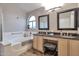 Bathroom featuring soaking tub, double sinks, granite countertops, and decorative mirrors at 11540 W Sonoran Ct, Surprise, AZ 85378