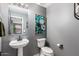 Charming powder room featuring pedestal sink, modern fixtures, and soothing gray walls and accent art at 11737 W Robin Dr, Sun City, AZ 85373