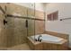 Close-up view of the soaking tub and frameless shower with decorative tile details at 12436 S 38Th Pl, Phoenix, AZ 85044