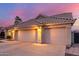 Spacious three-car garage with tile roof, complemented by desert landscaping and an illuminated address at dusk at 2040 E Indigo Brush Rd, Phoenix, AZ 85048