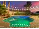 Backyard pool at dusk, featuring string lights, mature landscaping and tiled pool edging at 2040 E Indigo Brush Rd, Phoenix, AZ 85048