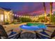 Inviting pool area with lounge chairs, lush landscaping, and ambient lighting at dusk at 2040 E Indigo Brush Rd, Phoenix, AZ 85048