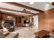 Cozy living room features wood paneled walls, ceiling beams, and a brick fireplace at 2148 E Cairo Dr, Tempe, AZ 85282
