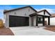 Charming single-story home with a black garage door and desert landscaping at 23403 W Albeniz Pl, Buckeye, AZ 85326