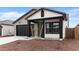 View of a charming single-story home with a black garage door and desert landscaping at 23403 W Albeniz Pl, Buckeye, AZ 85326