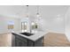 Kitchen island with bar seating and pendant lights, seamlessly flowing into the living space at 23403 W Albeniz Pl, Buckeye, AZ 85326