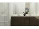 Well-lit bathroom with a double sink vanity, dark wood cabinets, and a glass-enclosed shower at 5043 S 233Rd Dr, Buckeye, AZ 85326