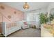 Well-decorated Bedroom with pink accent wall, crib, rocker and views to the backyard at 5206 S Clark Dr, Tempe, AZ 85283