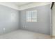 Bedroom featuring gray walls, a window, concrete floors, and light trim at 54463 W Sunburst St, Maricopa, AZ 85139