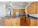Spacious kitchen boasts wooden cabinets, granite countertops, stainless appliances, and terracotta tile floors at 54463 W Sunburst St, Maricopa, AZ 85139