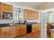 Large kitchen with wooden cabinets, granite countertops, stainless steel appliances, and terracotta tile flooring at 54463 W Sunburst St, Maricopa, AZ 85139