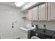 Functional laundry room with white washer and black dryer, along with upper cabinets at 5513 E Grovers Ave, Scottsdale, AZ 85254