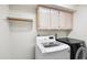 Well-lit laundry room featuring a white washer and black dryer, as well as white cabinets at 5513 E Grovers Ave, Scottsdale, AZ 85254