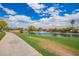 Scenic view of a community pond with a water fountain feature, lush greenery, and upscale residential homes at 7170 W Crystal Rd, Glendale, AZ 85308