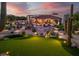 Expansive backyard with putting green, pool, desert landscaping, and cozy outdoor living area at dusk at 7788 E Morning Vista Ln, Scottsdale, AZ 85266