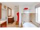 Bright bathroom featuring a sink with wood cabinet, large mirror, and a soaking tub with tile surround at 9015 E Altadena Ave, Scottsdale, AZ 85260