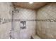 Close-up of a tiled shower with stone accents, multiple shower heads, and built-in shelving for toiletries at 9015 E Altadena Ave, Scottsdale, AZ 85260