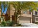 Tan two-story home with a two-car garage and a small balcony, accented by a yellow flowering tree at 1564 W Redwood Ln, Phoenix, AZ 85045