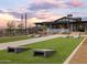 A view of the lawn with benches, desert landscaping, and two cornhole setups at sunset at 16084 W Prickly Pear Trl, Surprise, AZ 85387