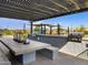 Outdoor kitchen featuring built-in grill, countertop, seating, pergola, and nearby playground at 16084 W Prickly Pear Trl, Surprise, AZ 85387