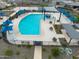 Aerial view of community pool showcasing seating, umbrellas, playground, and basketball court at 16084 W Prickly Pear Trl, Surprise, AZ 85387