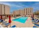 Community pool area with lounge chairs, umbrellas, tables, and a view of the surrounding buildings at 7960 E Camelback Rd # 110, Scottsdale, AZ 85251