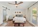 Bedroom with a ceiling fan, an upholstered chair, french doors to the patio, and a sliding barn door to the bath at 10832 N 37Th St, Phoenix, AZ 85028