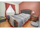 Bedroom showcasing a wooden frame bed, wood flooring, and a large window with red curtains at 1123 N Agave St, Casa Grande, AZ 85122