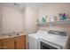 Bright laundry room featuring wooden cabinets, a stainless steel sink, and modern washer and dryer units at 1123 N Agave St, Casa Grande, AZ 85122