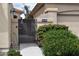 Exterior view of a desert home featuring a decorative wrought iron gate with flowering bushes and cacti at 11390 N 78Th St, Scottsdale, AZ 85260