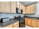 Updated kitchen with wood cabinets, black appliances, and modern fixtures at 11988 W Nadine Way, Peoria, AZ 85383