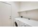 Clean laundry room with white washer, dryer, door, and a shelf at 11988 W Nadine Way, Peoria, AZ 85383