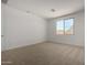 Well-lit bedroom featuring neutral carpet, white walls, and a window providing views of the neighborhood at 12366 W Marguerite Ave, Avondale, AZ 85323