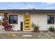 Close up shot of the bright yellow front door surrounded by desert landscaping and pink flowers at 13419 N 35Th St, Phoenix, AZ 85032