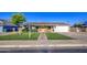 Charming single-story home with a well-manicured lawn, brick pathway, and a yellow front door at 1357 S Loma Vis, Mesa, AZ 85204