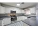 Well-lit kitchen featuring white cabinets, stainless steel appliances, stylish flooring, and modern countertops at 1357 S Loma Vis, Mesa, AZ 85204