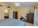 Bedroom with yellow walls, a ceiling fan, desk with chair, and door leading to the bathroom at 1414 W Grovers Ave, Phoenix, AZ 85023
