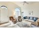 Sunlit living room featuring tile flooring, high ceilings, arched windows, and comfortable furnishings at 14300 W Bell Rd # 245, Surprise, AZ 85374