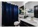 Stylish bathroom with navy blue curtain, white vanity, gold hardware, decorative flower arrangement, and artwork at 14733 N 159Th Dr, Surprise, AZ 85379