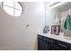 This bathroom features a round window, blue vanity and modern fixtures, offering a clean and inviting space at 14733 N 159Th Dr, Surprise, AZ 85379