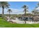 Picturesque view of a tranquil golf course pond with waterfall, mature trees, and golf course at 1556 E Vesper Trl, Queen Creek, AZ 85140